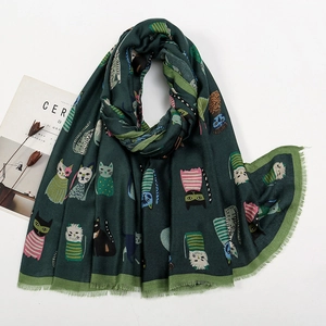 Detail of dark green scarf featuring colorful cartoon cat patterns and fringe edges