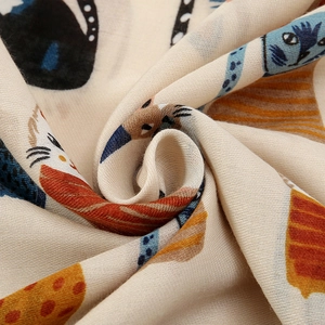 Detail of soft beige fabric with colorful cartoon cat and bird print on winter scarf