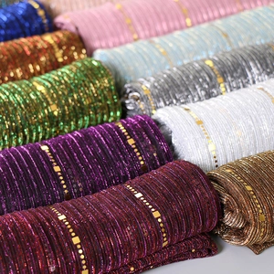 Close-up of sequin lace scarf fabric with glitter textures and gold metallic patterns