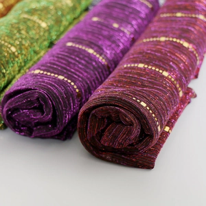 Detail of sequin lace scarf fabric showing green, purple and red textures with gold squares