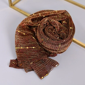 Detail of red-brown sequin lace scarf with pleated texture and metallic gold finish