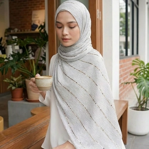 Light grey pleated hijab with golden sequins shown in a natural cafe setting