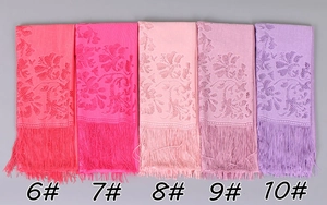 Detail of floral lace shawls with tassel fringe in coral, pink, and lilac color options