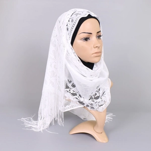 Detail of white hollow lace hijab shawl featuring intricate floral patterns and long tassels