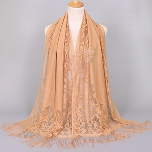 Detail of light brown lace shawl with intricate floral cutouts and delicate tassel fringe