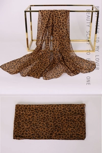Detail view of leopard print chiffon scarf draped on a gold metal display stand
