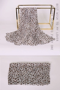 Detail of leopard print chiffon scarf on a gold metal stand with elegant folded layers