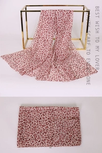Detail view of pink leopard print chiffon scarf with delicate edges on metal hanger