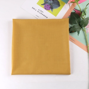 Detail of square mustard yellow folded scarf with fine texture in a lifestyle setting
