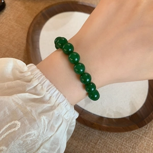 Retro style green agate bead bracelet on woman wrist with a dark wood background