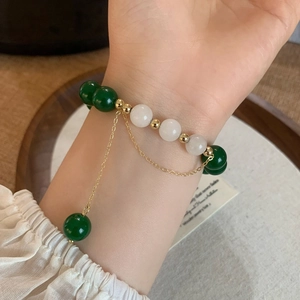 Vintage green agate and white jade beaded bracelet with gold tassel on a wrist