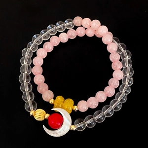 Detailed macro of a double-layer crystal bracelet featuring a white crescent moon charm