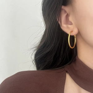 Close-up of minimalist matte golden hoop earrings worn by a model for a stylish look