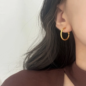 Close-up of a model wearing minimalist matte gold hoop earrings for everyday style