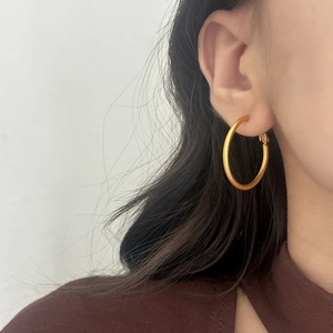 Detailed close-up of a matte gold hoop earring worn for a modern and minimalist style