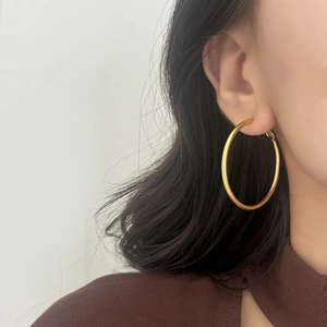 Close-up of model wearing large 5cm matte gold hoop earrings for daily commute