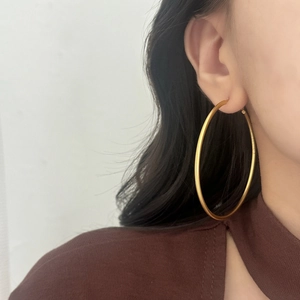Close-up of minimalist large gold hoop earrings on female model in a side view