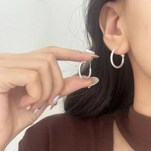 Close-up of matte silver hoop earrings with brushed metal texture and simple round design