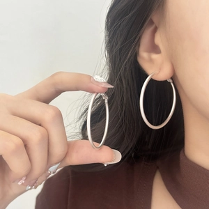 Detailed close-up of large matte silver hoop earrings shown on model for daily wear