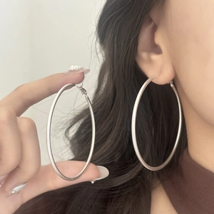 Detailed view of large matte silver hoop earrings worn to show the 5-6cm size and scale