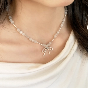 Collier élégant avec pendentif nœud argenté et perles opales sur le cou de femme