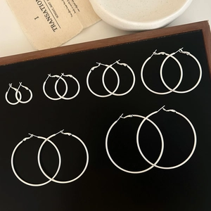 Set of six pairs of polished silver hoop earrings in various sizes on a black display