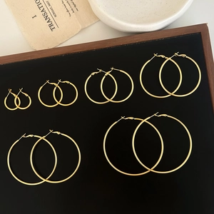 Set of six gold hoop earrings in varying sizes displayed on a minimalist jewelry tray