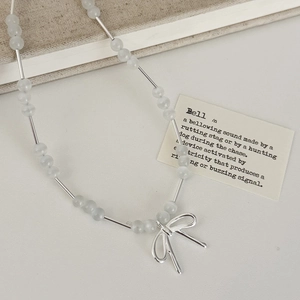 Détail du collier en perles d'œil de chat avec pendentif nœud en argent et tubes