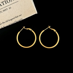 Detail view of large golden hoop earrings with elegant matte frosted finish on black background