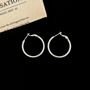 Macro detail of matte silver hoop earrings featuring a classic clasp on black velvet