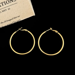 Detailed view of large classic gold hoop earrings with snap closure on black background