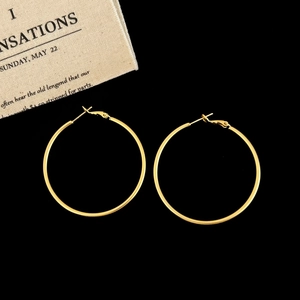 Detailed close-up of large golden hoop earrings on a black background for a luxury look
