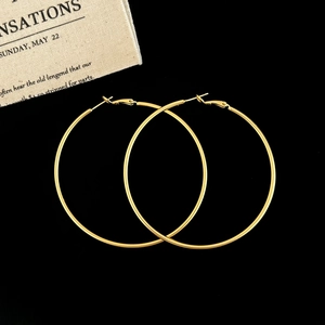 Detailed top view of large gold hoop earrings with snap closure on a black background