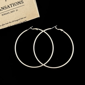 Macro view of large polished silver hoop earrings on a black background with fabric