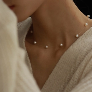 Elegant invisible fishing line necklace featuring round white pearls on a model