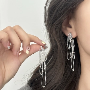 Elegant silver tassel drop earrings with long layered bead chains on a female model