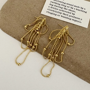 Detailed macro view of golden multi-layer bead chain fringe earrings with vintage texture