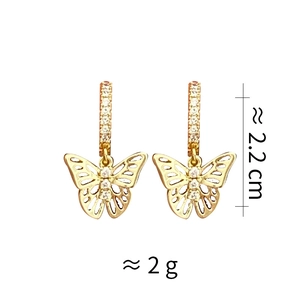 Détail de boucles d'oreilles papillon dorées avec zircones et indications de taille
