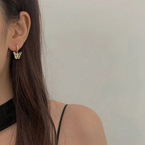 Gros plan de boucles d'oreilles papillon dorées avec zircon porté par un mannequin chic