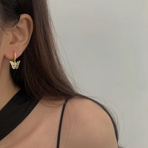 Élégantes boucles d'oreilles papillon dorées avec zircone sur un modèle féminin