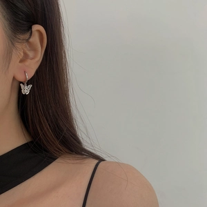 Détail d'une boucle d'oreille papillon plaquée or avec zircon sur un mannequin