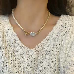 Detail of asymmetrical pearl and gold chain necklace with a baroque pearl drop pendant
