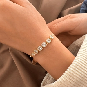 Elegant adjustable gold-plated bracelet with halo square-cut crystals on female wrist