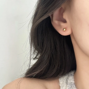 Minimalist high-polished golden ball stud earrings shown on model for daily wear