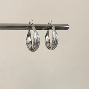 Close-up of Mobius silver earrings featuring polished and frosted textured interlocking rings