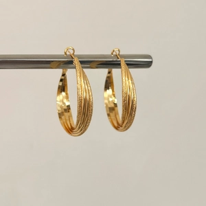 Close-up of golden Mobius hoop earrings with intertwined polished and frosted textures