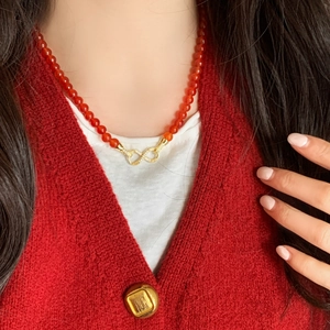 Elegant beaded necklace with red agate, pearls and infinity symbol worn by a model
