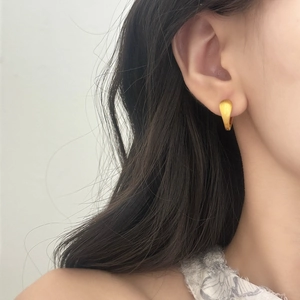 Boucles d'oreilles dorées en forme de U avec finition mate brossée sur modèle