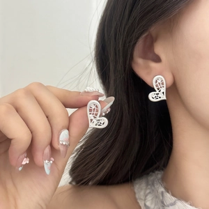 Elegant silver hollow heart stud earrings with cubic zirconia stones worn by a model