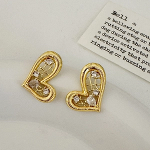 Detail of gold heart stud earrings featuring intricate wire wrapping and white crystals